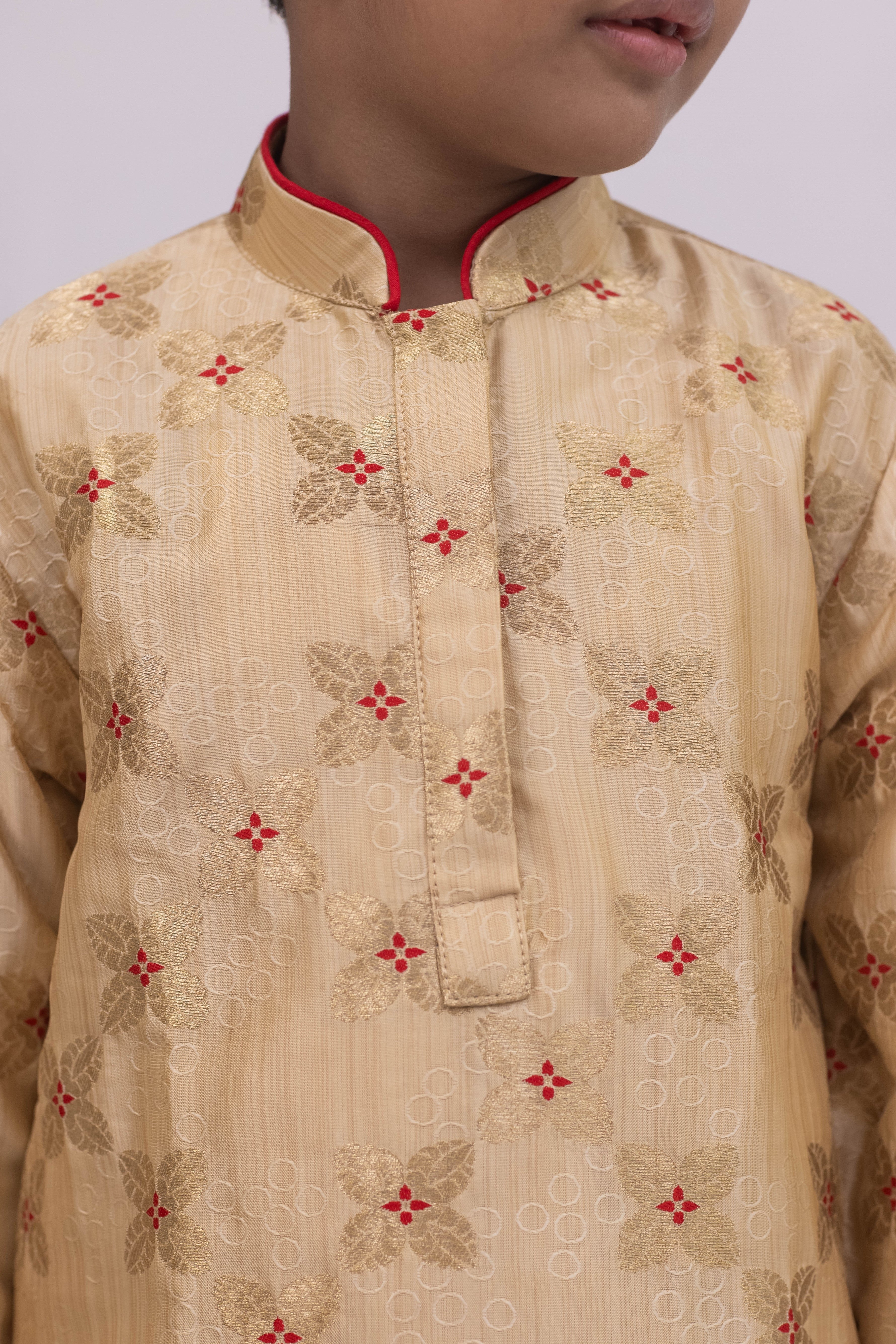 Beige banarasi brocade kurta set with a highlighted stand collar and front placket and red cotton silk chunidar salwar for Boys.Kurtas with collar or Angrakha pattern teamed with salwar are the best choice for any festive occasion for boys. They are Trendy, Easy to wear and comfortable to carry.