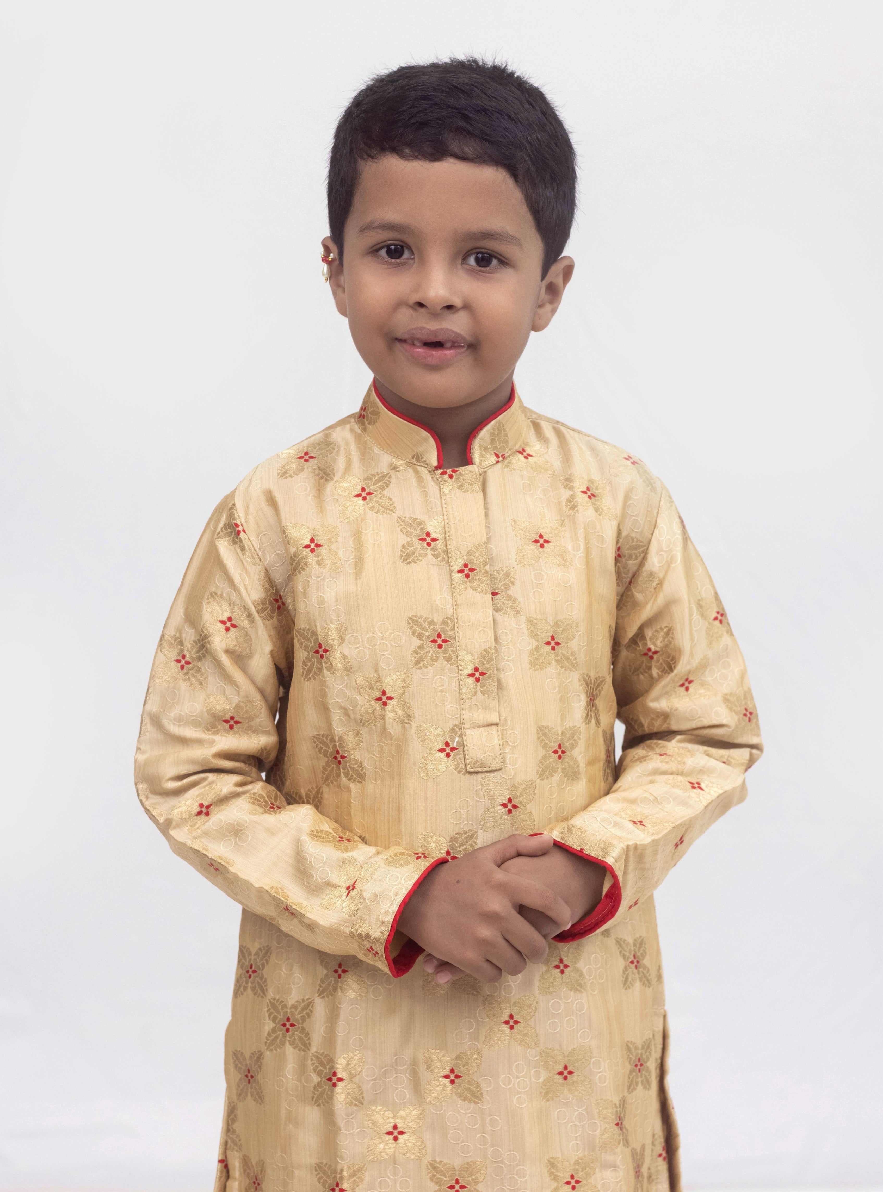 Beige banarasi brocade kurta set with a highlighted stand collar and front placket and red cotton silk chunidar salwar for Boys.Kurtas with collar or Angrakha pattern teamed with salwar are the best choice for any festive occasion for boys. They are Trendy, Easy to wear and comfortable to carry.