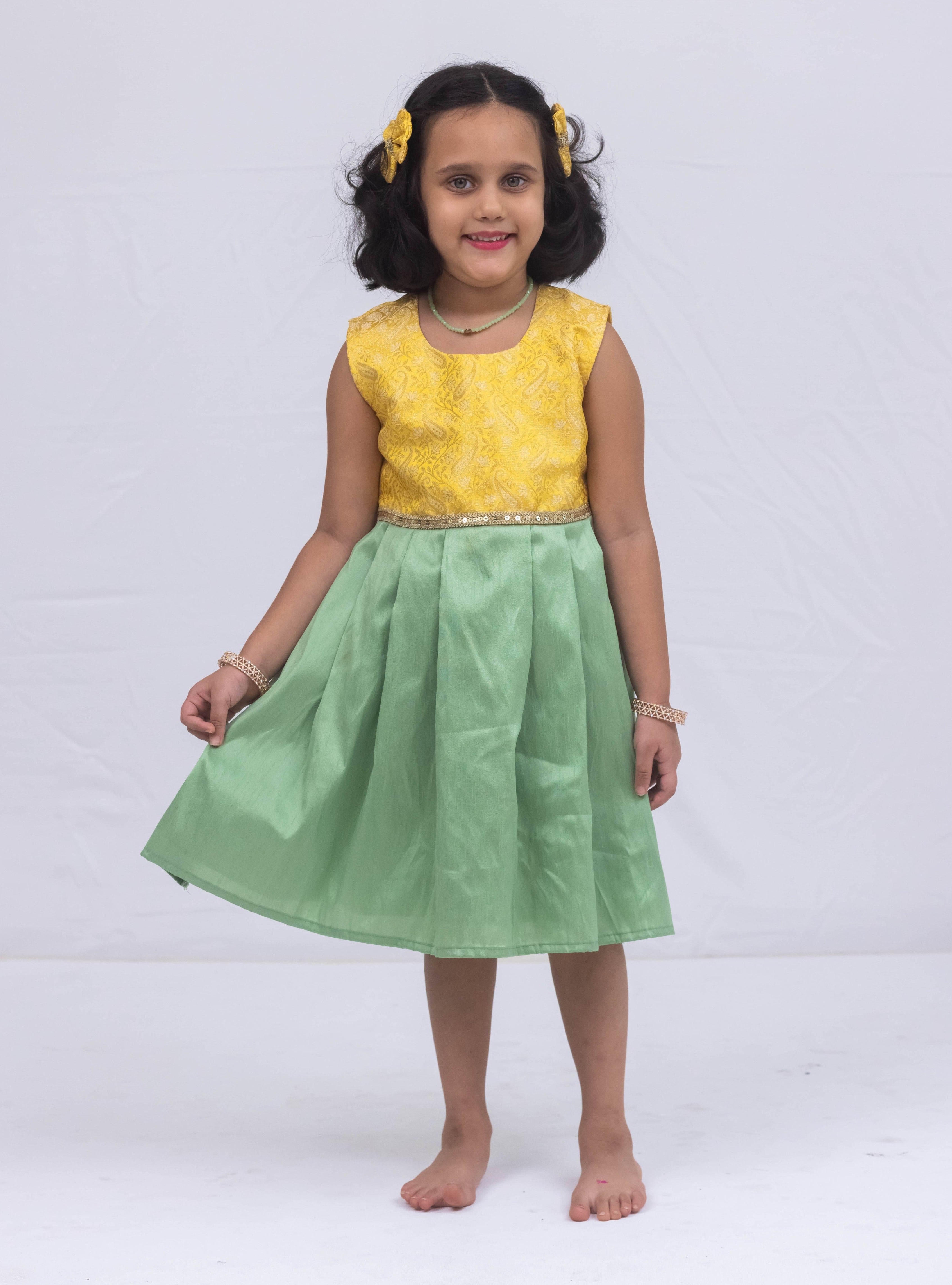 Introducing our latest product: a stunning yellow banarasi brocade yoke paired with a mint green raw silk pleated dress, complete with a delicate sequined lace waist detailing, designed specifically for girls. With its intricate craftsmanship and elegant color combination, this dress is sure to make a statement. Don't miss out on this unique addition to our collection!
