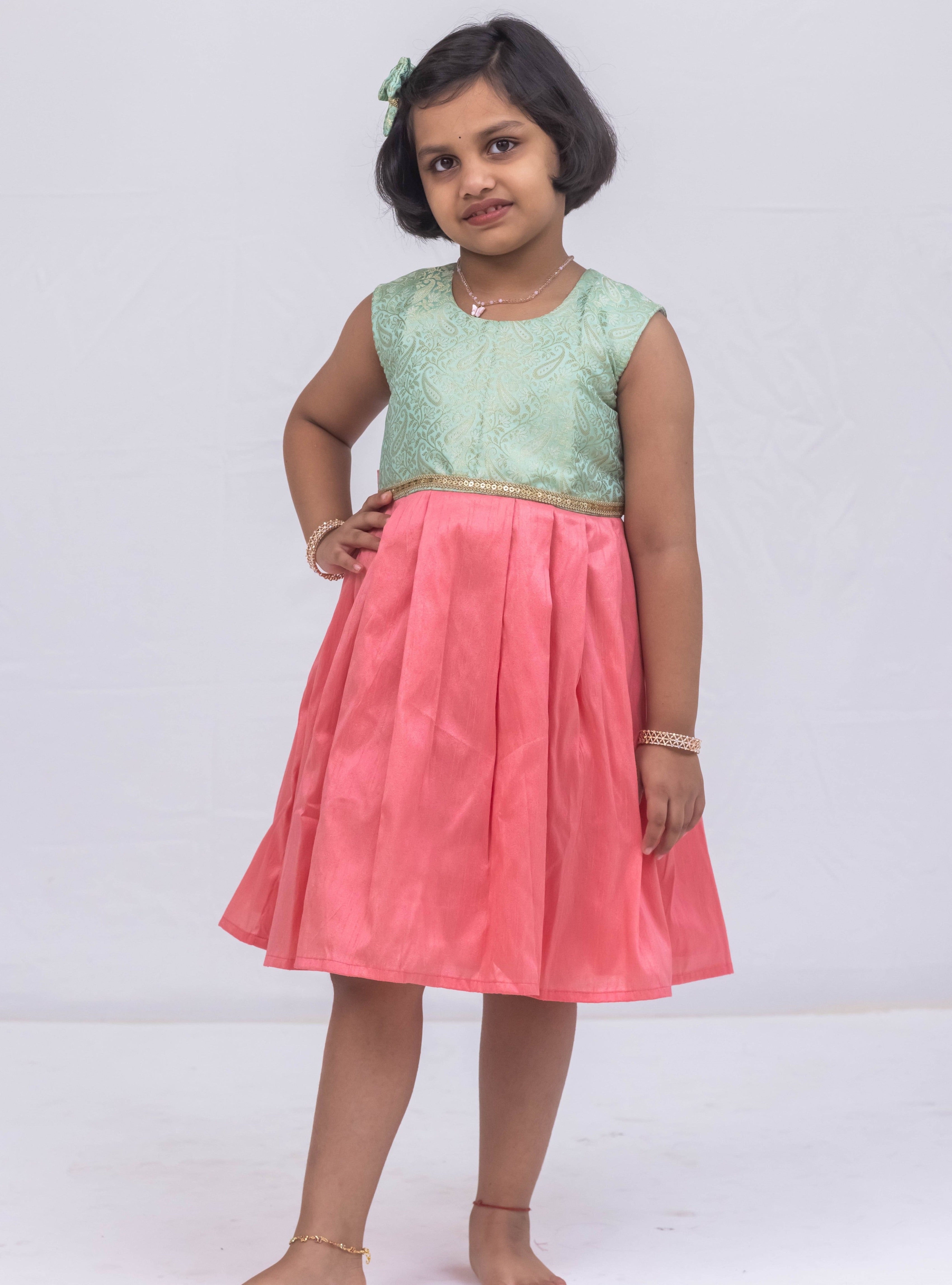 Introducing our latest product: a stunning Pista Green banarasi brocade yoke paired with a Rose Pink raw silk pleated dress, complete with a delicate sequined lace waist detailing, designed specifically for girls. With its intricate craftsmanship and elegant color combination, this dress is sure to make a statement. Don't miss out on this unique addition to our collection!