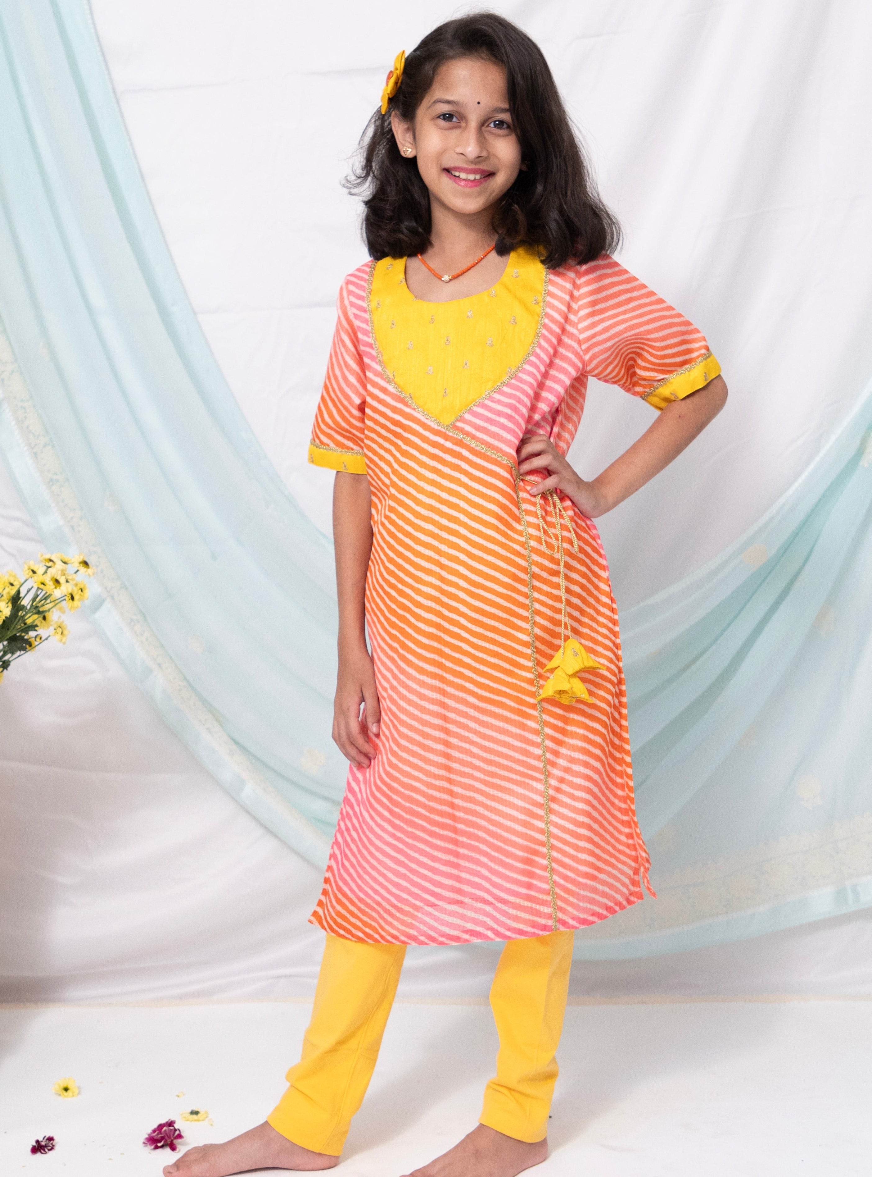 Pink and orange leheriya kotta chanderi kurti with yellow raw silk sequined yoke for Girls.Let your princess be as comfortable as in her casuals with carefully designed & crafted Comfort Ethnic Wear by Soyara Ethnics.Keep her fashion quotient high with timeless patterns, vibrant combinations and royal textiles.