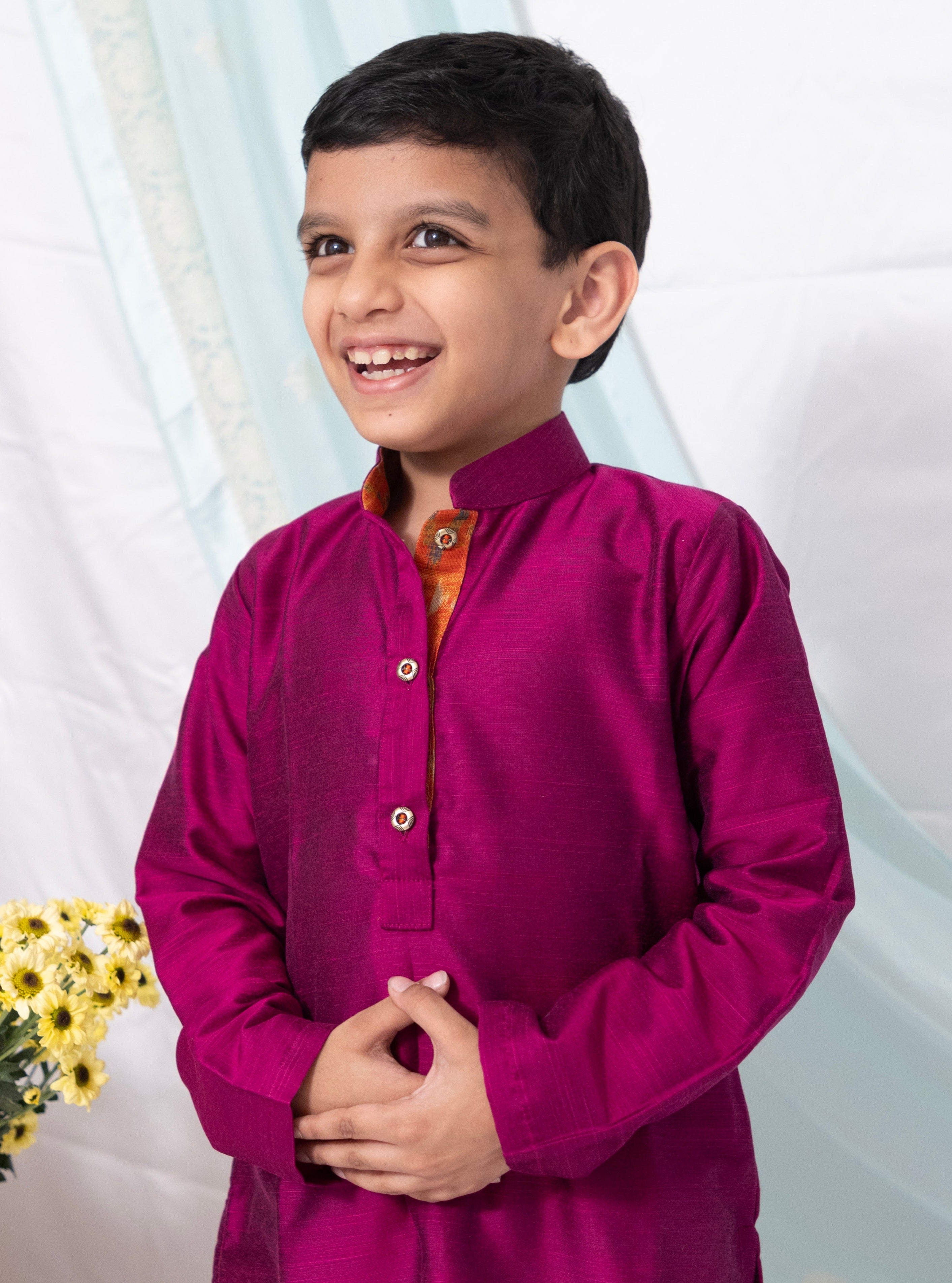 Enhance your traditional ensemble with this Magenta cotton silk kurta for Boys. Featuring a stand collar, orange placket detailing, and golden buttons, it can be paired with salwar or jeans for a stylish and comfortable look.