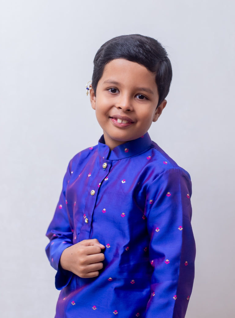 This Royal Blue taffeta silk kurta for boys features a stand collar and detailed zari embroidery. The placket is adorned with stone-studded buttons, and the kurta is lined with comfortable cotton for added ease.