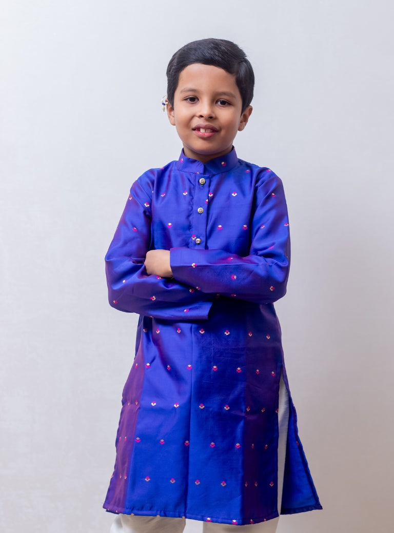 This Royal Blue taffeta silk kurta for boys features a stand collar and detailed zari embroidery. The placket is adorned with stone-studded buttons, and the kurta is lined with comfortable cotton for added ease.