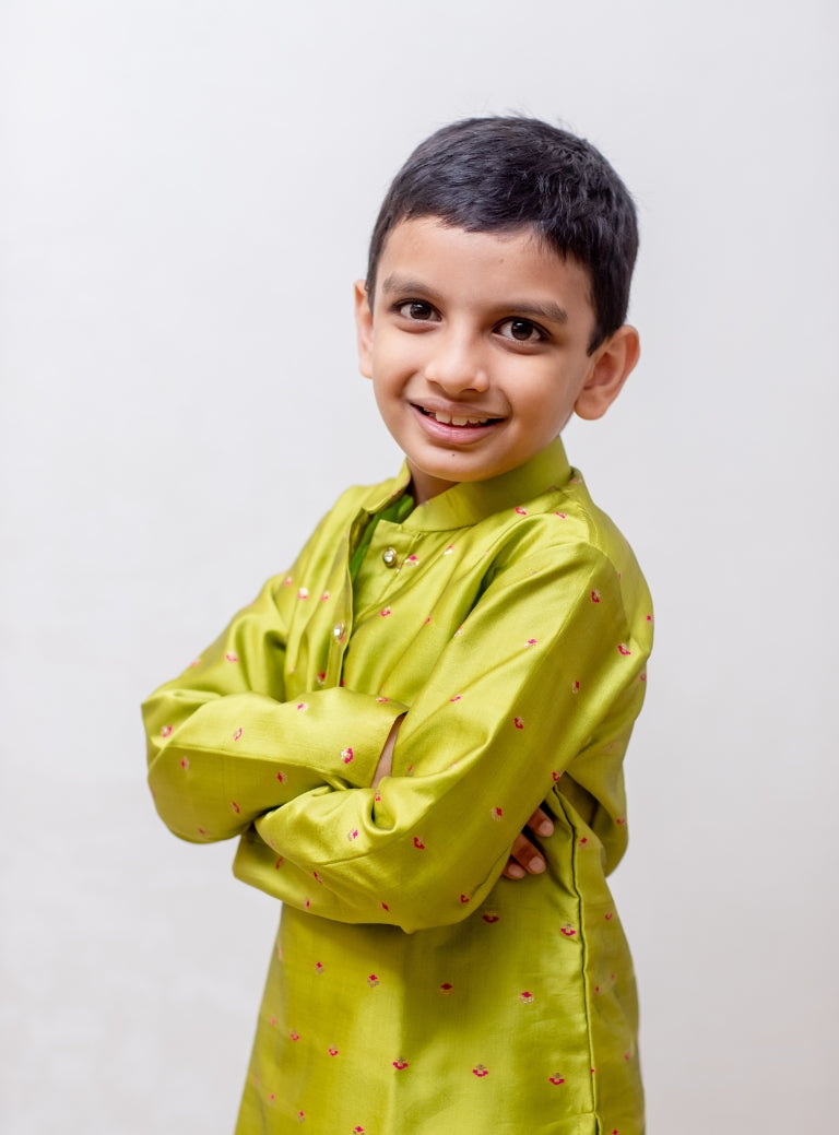 This parrot green taffeta silk kurta for boys features a stand collar and detailed zari embroidery. The placket is adorned with stone-studded buttons, and the kurta is lined with comfortable cotton for added ease.