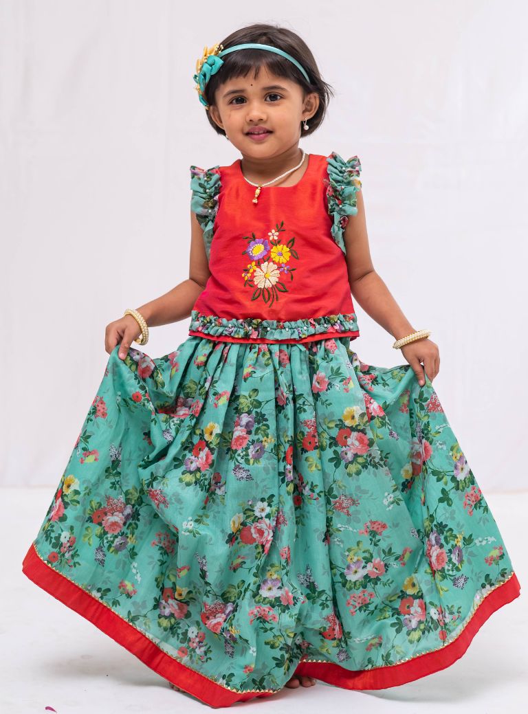 This Cyan coloured ghagra is flaunting floral prints and is crafted in chanderi. Featuring ruffled sleeves in raw silk embroidered orange choli, the sleeves are further highlighted with pearl embellishments. The orange border of the ghagra is adorned with gotta Patti embellishments.