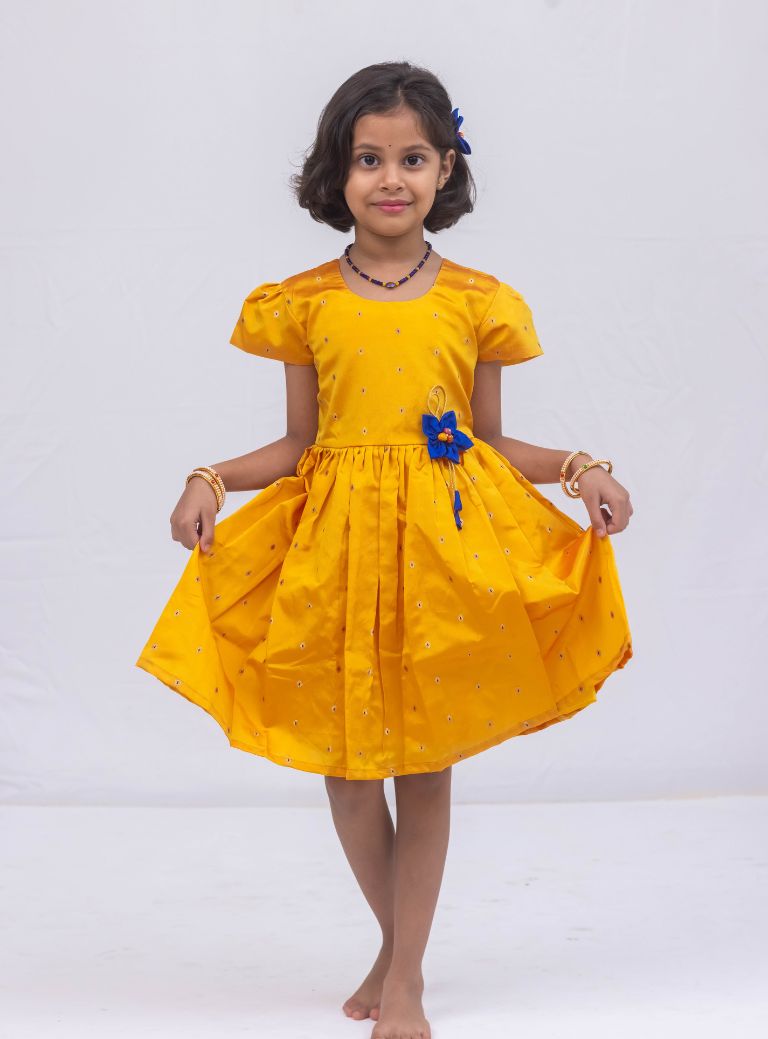 This stunning dress is made of yellow taffeta silk and features elegant puff sleeves. The dress also includes a delicate handmade fabric flower brooch, adding a touch of sophistication. A matching blue hair clip is included for a coordinated look.