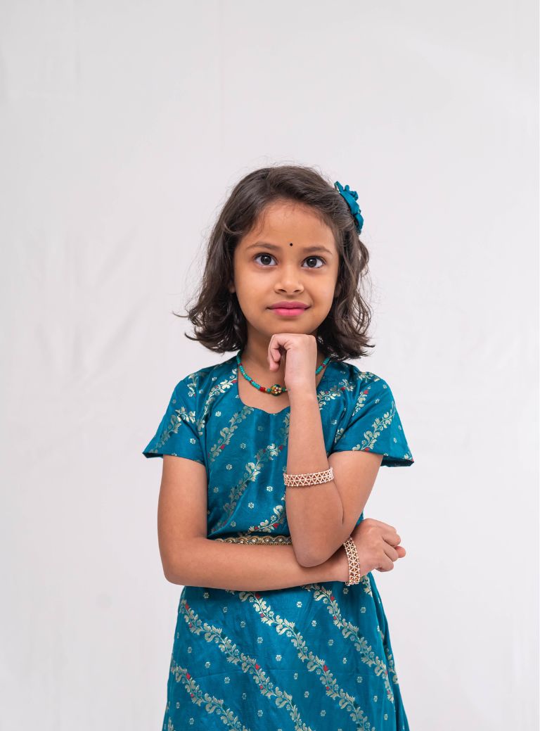 Peacock green banaras satin brocade silk gown with cap sleeves and ruffled flare for Girls.Let your princess be as comfortable as in her casuals with carefully designed & crafted Comfort Ethnic Wear by Soyara Ethnics.Keep her fashion quotient high with timeless patterns, vibrant combinations and royal textiles.
