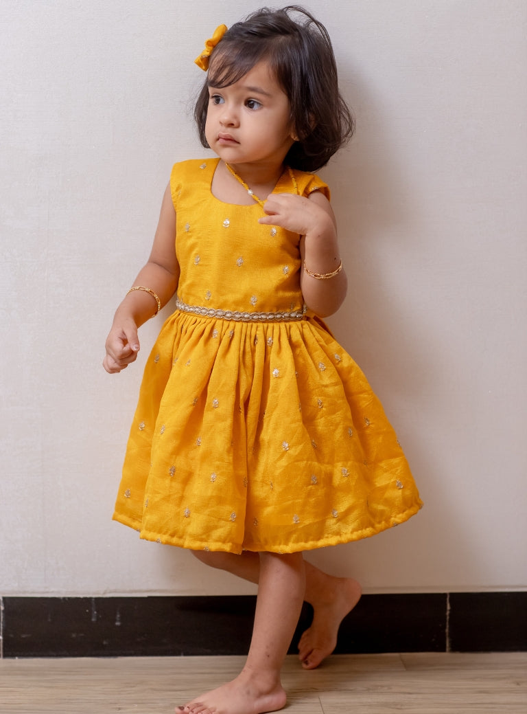 Royal Yellow Vichitra silk sleeveless dress for Girls.Let your princess be as comfortable as in her casuals with carefully designed and crafted Comfort Ethnic Wear by Soyara Ethnics. Keep her fashion quotient high with timeless patterns, vibrant combinations and royal textiles.