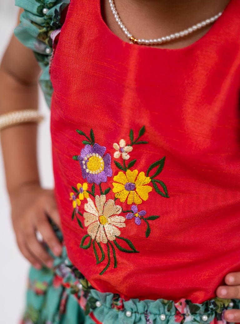 This Cyan coloured ghagra is flaunting floral prints and is crafted in chanderi. Featuring ruffled sleeves in raw silk embroidered orange choli, the sleeves are further highlighted with pearl embellishments. The orange border of the ghagra is adorned with gotta Patti embellishments.