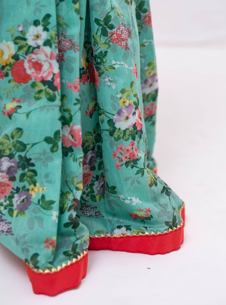 This Cyan coloured ghagra is flaunting floral prints and is crafted in chanderi. Featuring ruffled sleeves in raw silk embroidered orange choli, the sleeves are further highlighted with pearl embellishments. The orange border of the ghagra is adorned with gotta Patti embellishments.