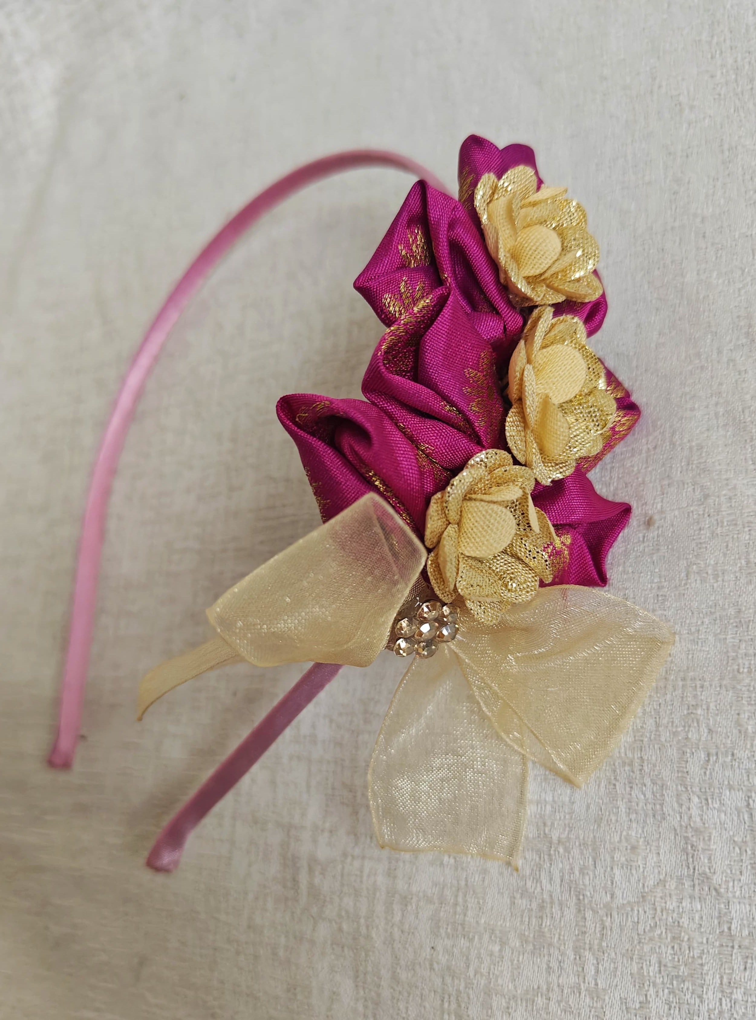 This Magenta flowers with violet headband  for girls features delicate fabric flowers and is handcrafted with great care. It is ideal for girls over the age of 2 and makes a lovely addition to any outfit.