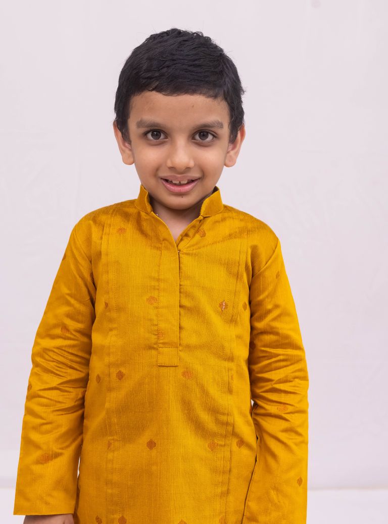 This Mustered Yellow kurta for boys features a knife pleated design crafted from raw silk. Adorned with jari buttas, it boasts a stand collar and front placket opening for a sophisticated touch. The cotton lining on the inside ensures comfort and quality.