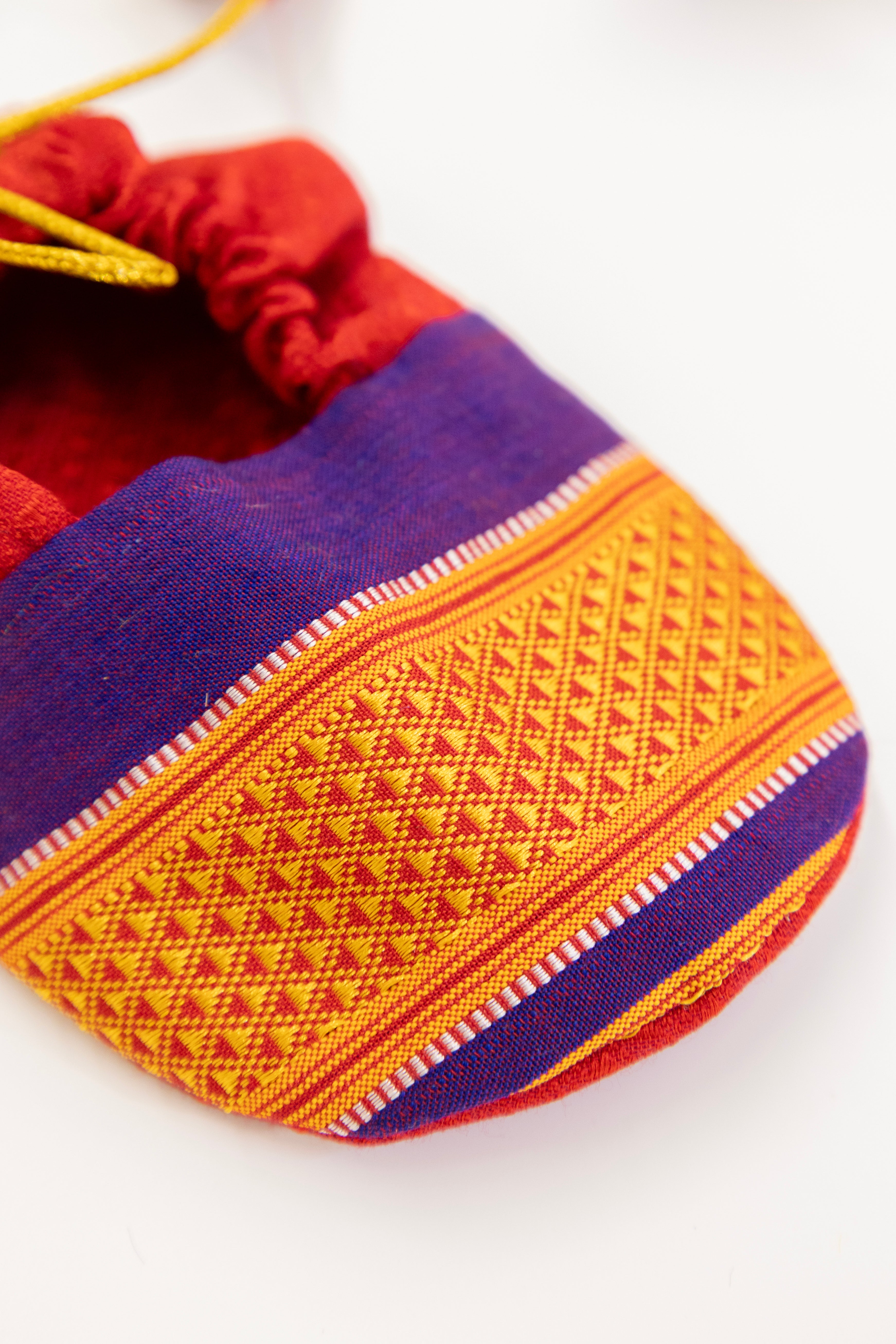Red handloom khunn with purple border topda / topi/ bonnet with coordinated khunn booties set for NewBorn. Handcrafted accessories for Newborn are perfect add ons to any traditional attire of the baby.Designer baby mats,set of generic bloomers are other naming ceremony essentials.