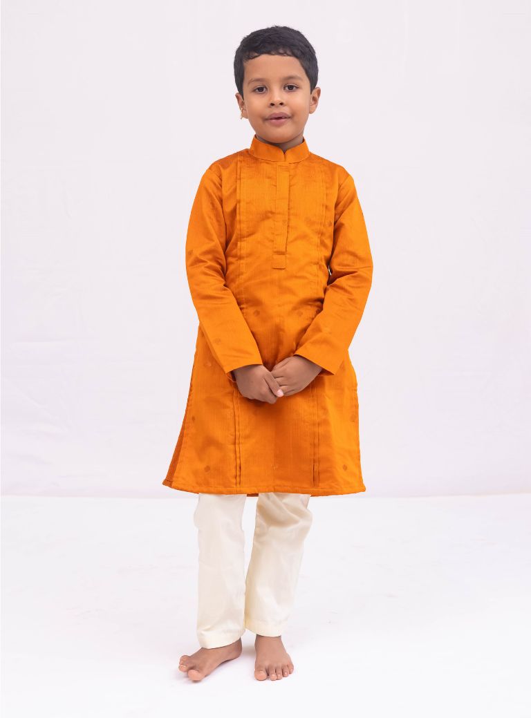 This Rust colored kurta for boys features a knife pleated design crafted from raw silk. Adorned with jari buttas, it boasts a stand collar and front placket opening for a sophisticated touch. The cotton lining on the inside ensures comfort and quality.