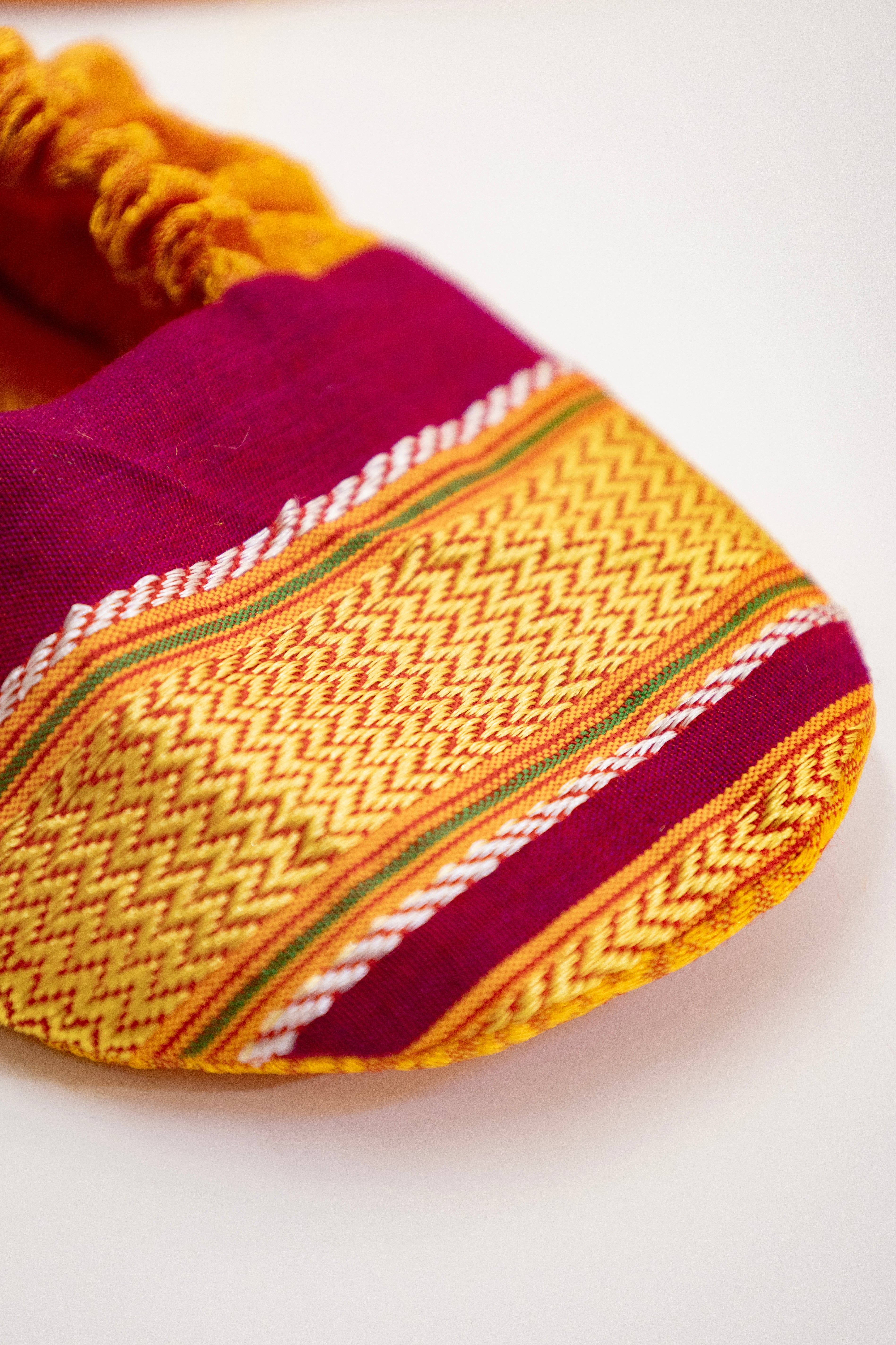 Yellow handloom khunn with crimson border topda / topi/ bonnet with coordinated khunn booties set for NewBorn. Handcrafted accessories for Newborn are perfect add ons to any traditional attire of the baby.Designer baby mats,set of generic bloomers are other naming ceremony essentials.
