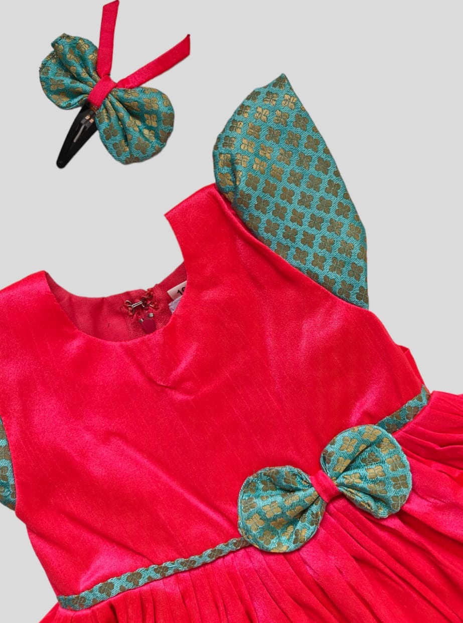Candy Pink Raw silk dress with sky blue brocade sleeves and bow highlights for Girls.Let your princess be as comfortable as in her casuals with carefully designed & crafted Comfort Ethnic Wear by Soyara Ethnics.Keep her fashion quotient high with timeless patterns, vibrant combinations and royal textiles.