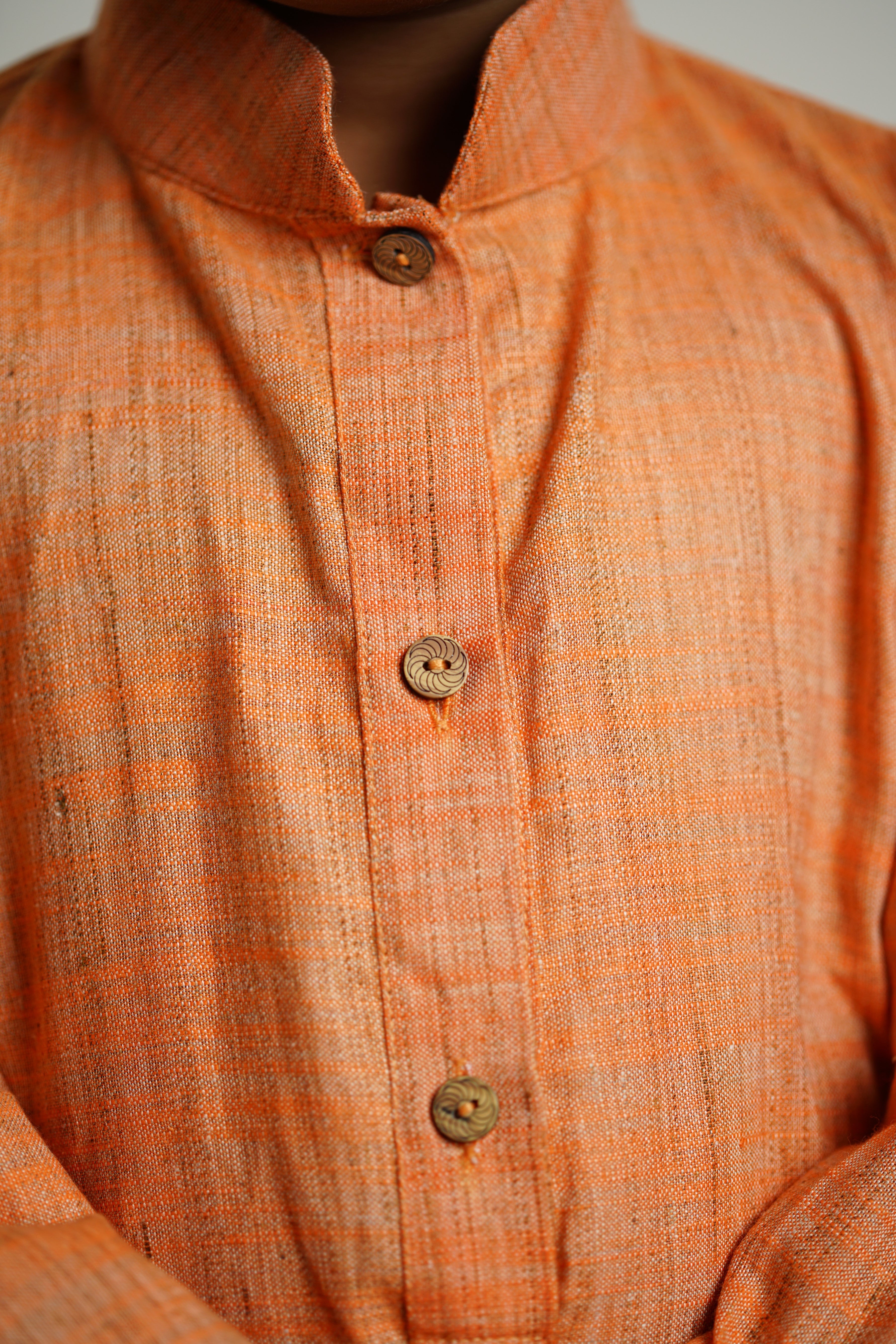 Light Orange Khadi silk stand collar long kurta with wooden buttons.Kurtas with collar or Angrakha pattern teamed with salwar are the best choice for any festive occasion for boys.They are Trendy, Easy to wear and comfortable to carry.