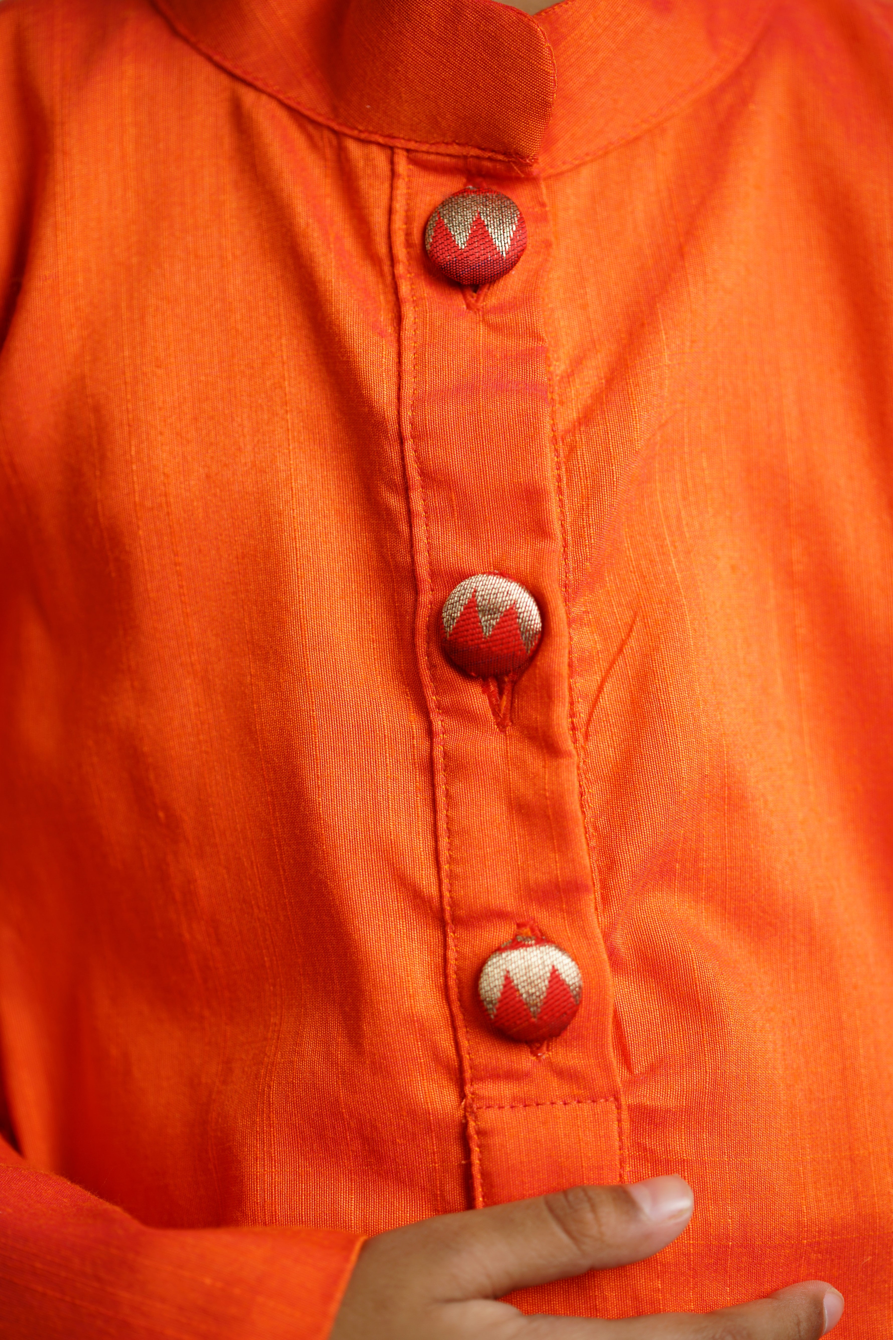 Orange cotton silk kurta with paithani fabric buttons.Kurtas with collar or Angrakha pattern teamed with salwar are the best choice for any festive occasion for boys.They are Trendy, Easy to wear and comfortable to carry.