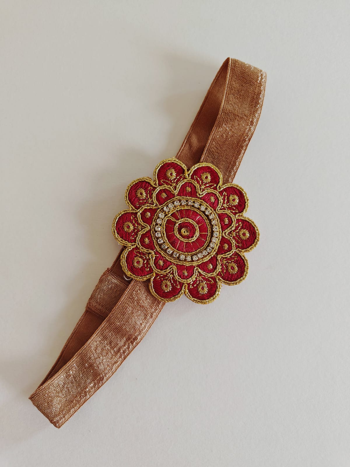 Embroidered stone embellished flower shaped stretchable headband for baby girl.Golden brocade bonnet,paithani booties,fabric headbands all these Handcrafted accessories for Newborn are perfect add ons to any traditional attire.Designer baby mats, set of generic bloomers are the other naming ceremony essentials.