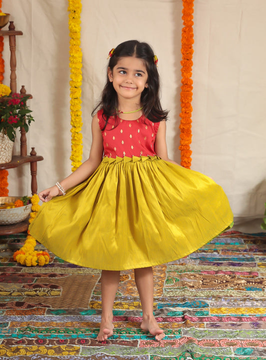 Red brocade short bodice frock with olive green raw silk bottom for girl.Let your princess be as comfortable as in her casuals with carefully designed & crafted Comfort Ethnic Wear by Soyara Ethnics.Keep her fashion quotient high with timeless patterns, vibrant combinations and royal textiles.