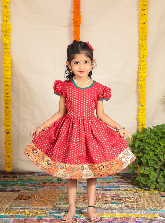 Red coloured Banaras brocade flared dress with paithani border for girl.Let your princess be as comfortable as in her casuals with carefully designed & crafted Comfort Ethnic Wear by Soyara Ethnics.Keep her fashion quotient high with timeless patterns, vibrant combinations and royal textiles.