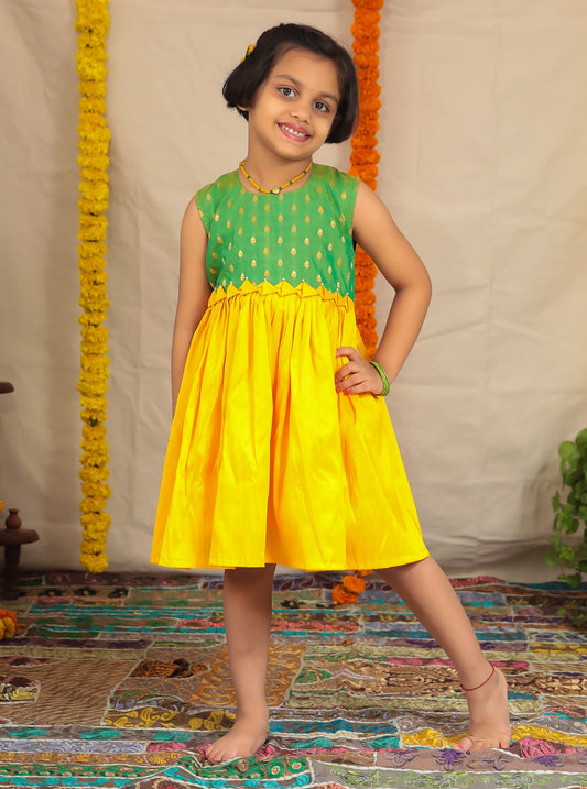 Green brocade short bodice frock with yellow raw silk bottom for girl.Let your princess be as comfortable as in her casuals with carefully designed & crafted Comfort Ethnic Wear by Soyara Ethnics.Keep her fashion quotient high with timeless patterns, vibrant combinations and royal textiles.