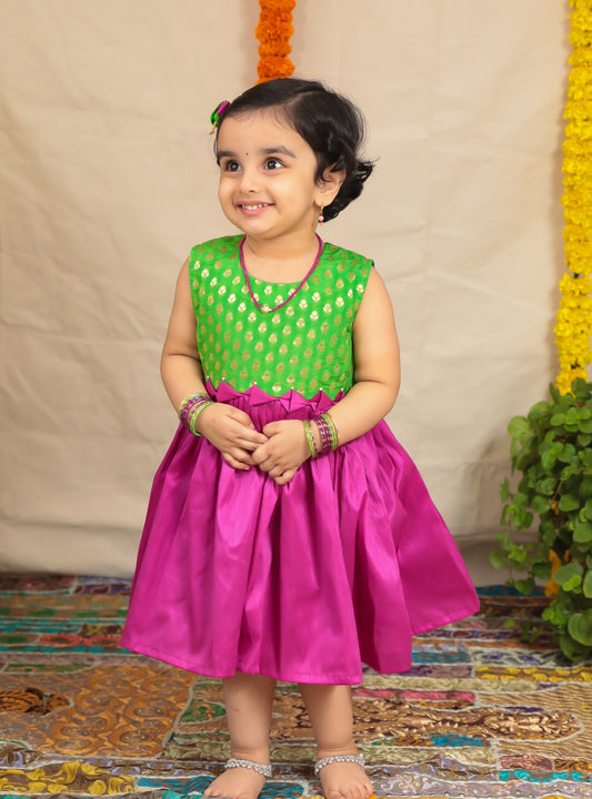 Parrot Green brocade short bodice frock with magenta raw silk bottom.Let your princess be as comfortable as in her casuals with carefully designed & crafted Comfort Ethnic Wear by Soyara Ethnics.Keep her fashion quotient high with timeless patterns, vibrant combinations and royal textiles.
