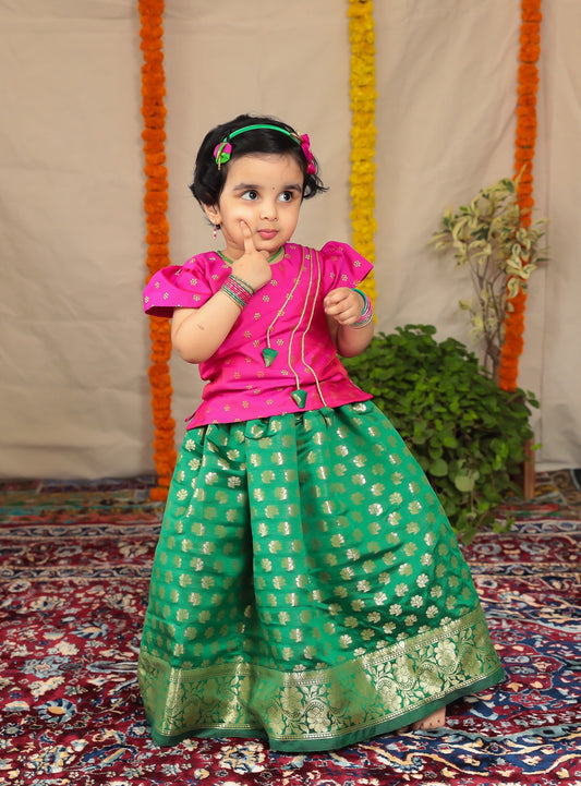 Green Banaras brocade parkar with intricate woven Border teamed with Rani pink soft brocade Polka.Let your princess be as comfortable as in her casuals with carefully designed & crafted Comfort Ethnic Wear by Soyara Ethnics.Keep her fashion quotient high with timeless patterns, vibrant combinations and royal textiles.
