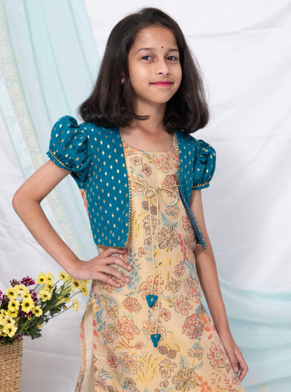 This beige floral printed tissue kurti comes with teal brocade silk false shrugs. The puffed sleeves and jacket feature intricate gotta patti detailing. The kurti is adorned with charming latkans and the chord ties add a touch of fun.