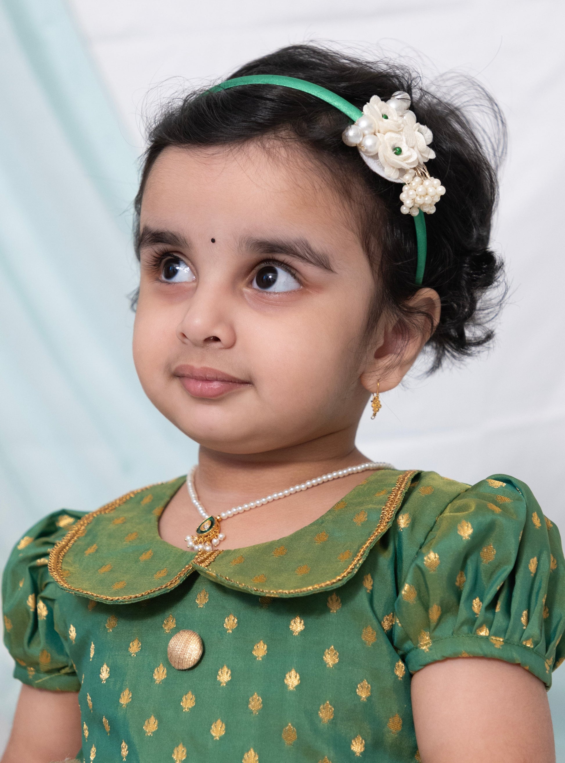 Green brocade silk and Ivory Mysore silk dress with Peter pan collar and puffed sleeves for Girl.Let your princess be as comfortable as in her casuals with carefully designed & crafted Comfort Ethnic Wear by Soyara Ethnics.Keep her fashion quotient high with timeless patterns, vibrant combinations and royal textiles.