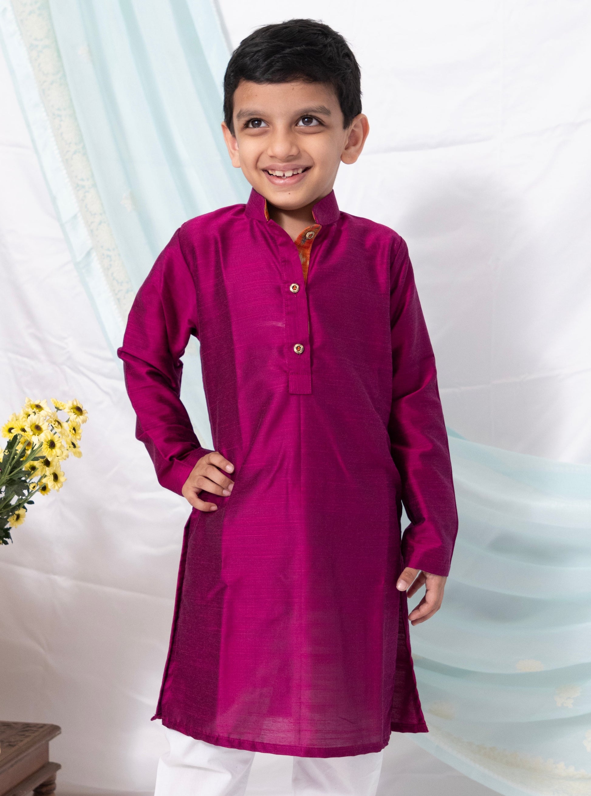 Enhance your traditional ensemble with this Magenta cotton silk kurta for Boys. Featuring a stand collar, orange placket detailing, and golden buttons, it can be paired with salwar or jeans for a stylish and comfortable look.