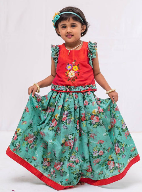 This Cyan coloured ghagra is flaunting floral prints and is crafted in chanderi. Featuring ruffled sleeves in raw silk embroidered orange choli, the sleeves are further highlighted with pearl embellishments. The orange border of the ghagra is adorned with gotta Patti embellishments.