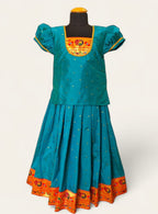 This Firozi Brocade silk parkar polka boasts an intricate Paithani border and yoke pattern, designed specifically for girls. The addition of puff sleeves accented with golden lace adds a touch of elegance to the garment.