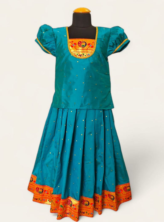 This Firozi Brocade silk parkar polka boasts an intricate Paithani border and yoke pattern, designed specifically for girls. The addition of puff sleeves accented with golden lace adds a touch of elegance to the garment.