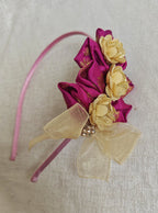 This Magenta flowers with violet headband&nbsp; for girls features delicate fabric flowers and is handcrafted with great care. It is ideal for girls over the age of 2 and makes a lovely addition to any outfit.