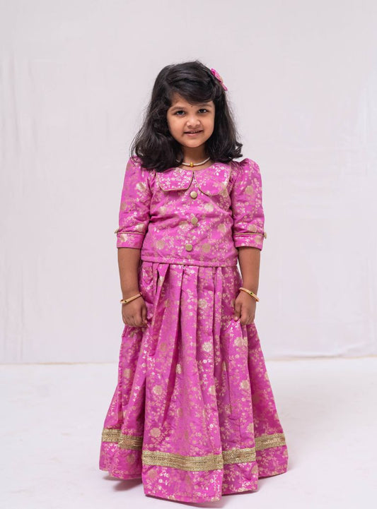 This Lilac banaras brocade ghagra is complemented by a Peterpan collared mutton sleeved choli.Let your princess be as comfortable as in her casuals with carefully designed & crafted Comfort Ethnic Wear by Soyara Ethnics.Keep her fashion quotient high with timeless patterns, vibrant combinations and royal textiles.