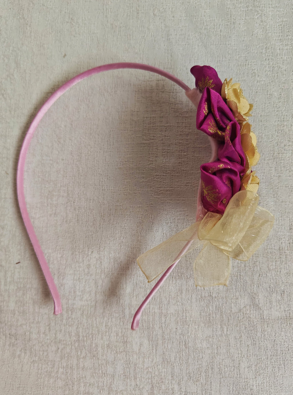 This Magenta flowers with violet headband&nbsp; for girls features delicate fabric flowers and is handcrafted with great care. It is ideal for girls over the age of 2 and makes a lovely addition to any outfit.