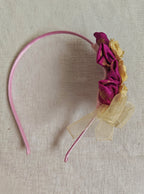 This Magenta flowers with violet headband&nbsp; for girls features delicate fabric flowers and is handcrafted with great care. It is ideal for girls over the age of 2 and makes a lovely addition to any outfit.