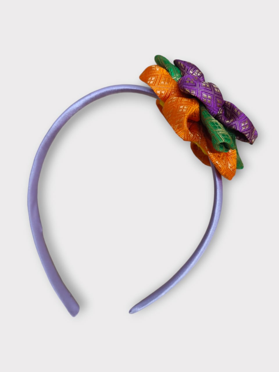 Magenta brocade layered flower motif , satin wrapped plastic hairband for Girls.This magenta brocade hairband features a layered flower motif and is wrapped in satin-covered plastic. It is perfect for girls aged two and up, making it a charming accessory for any outfit.