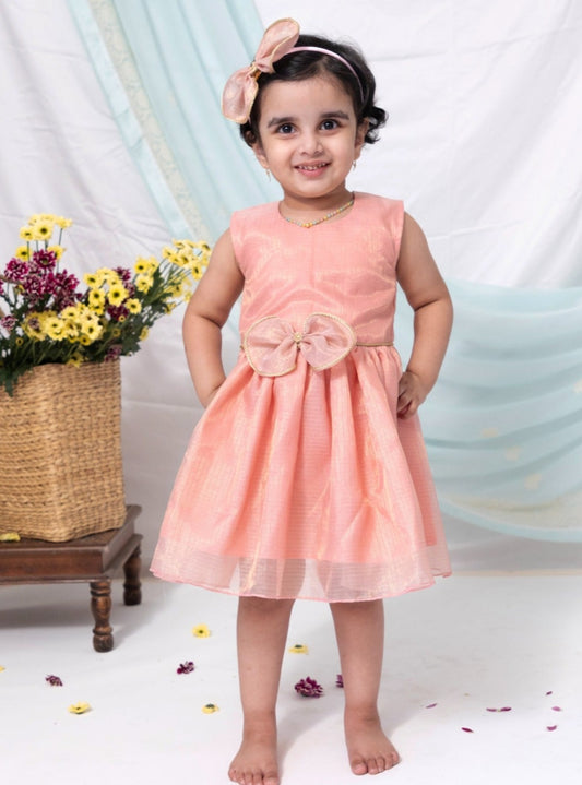 Pink tissue kotta silk sleeveless flared dress with statement embellished bow for Girl.Let your princess be as comfortable as in her casuals with carefully designed and crafted Comfort Ethnic Wear by Soyara Ethnics. Keep her fashion quotient high with timeless patterns, vibrant combinations and royal textiles.