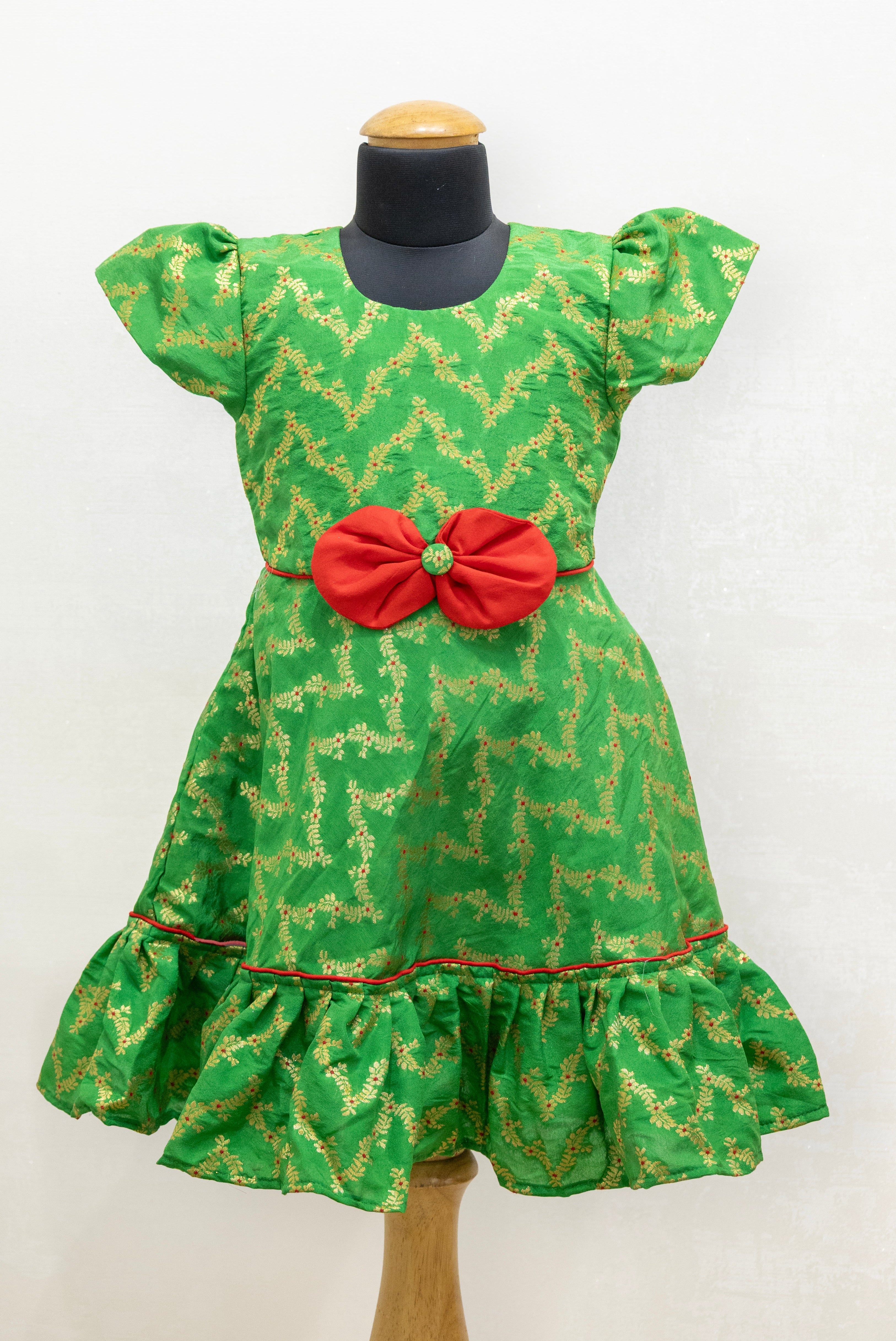 Green brocade silk flared dress with puffed sleeves and contrast red bow at the waistline for Girls