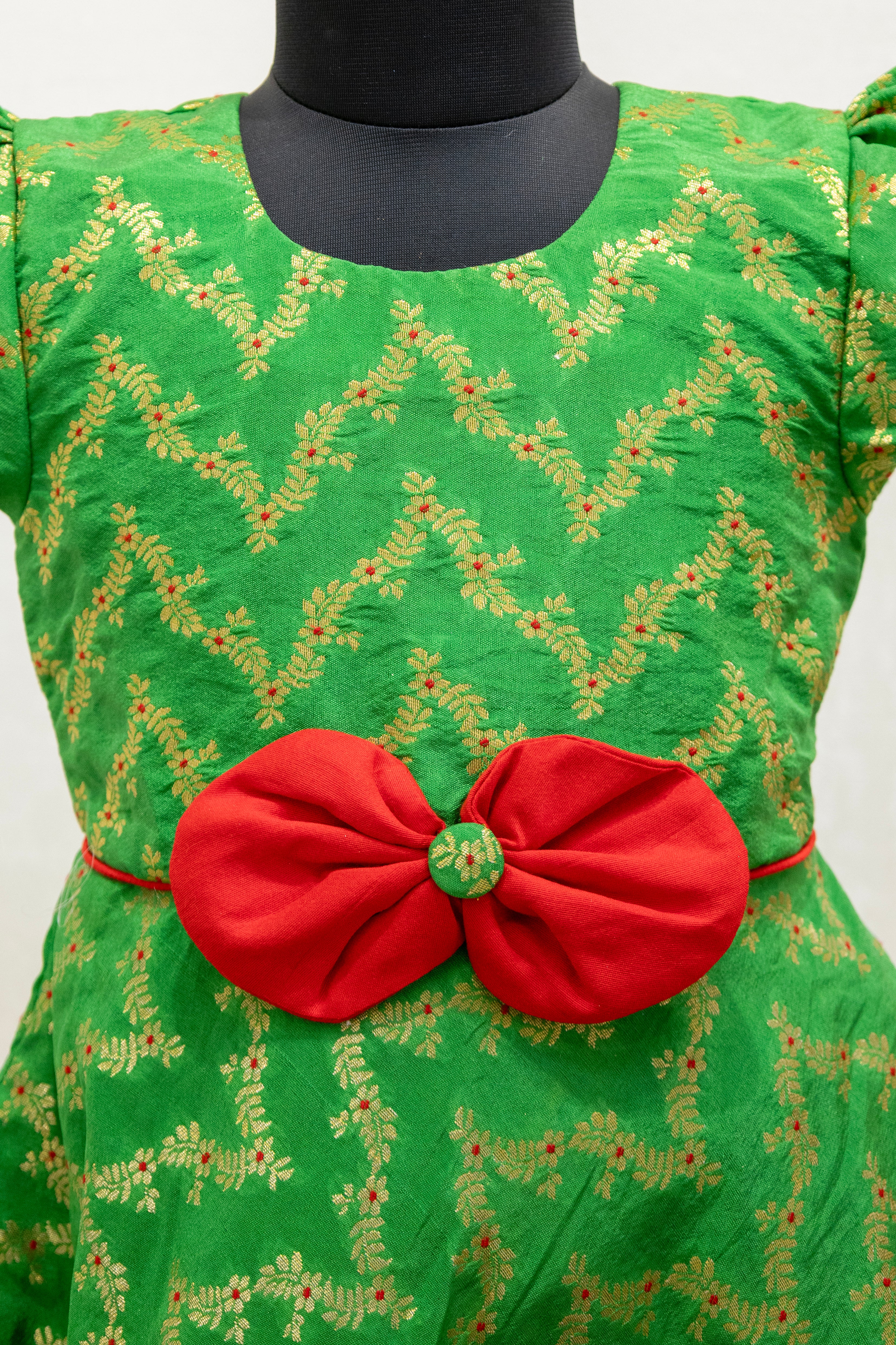 Green brocade silk flared dress with puffed sleeves and contrast red bow at the waistline for Girls