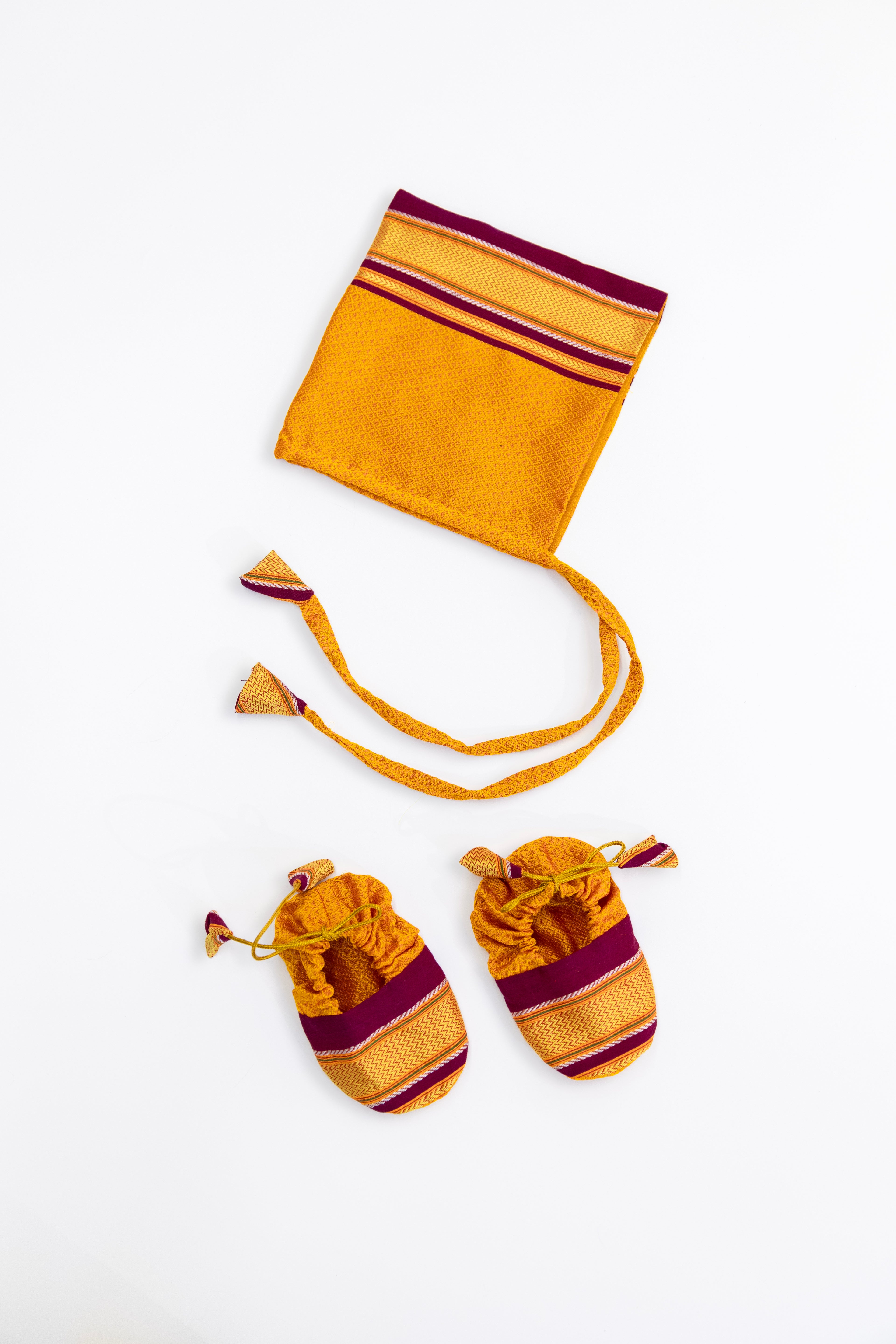 Yellow handloom khunn with crimson border topda / topi/ bonnet with coordinated khunn booties set for NewBorn. Handcrafted accessories for Newborn are perfect add ons to any traditional attire of the baby.Designer baby mats,set of generic bloomers are other naming ceremony essentials.