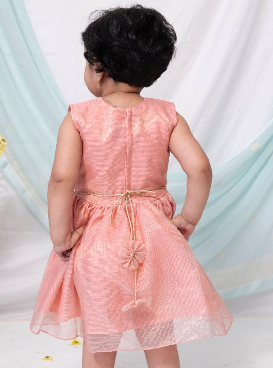 Pink tissue kotta fabric has a subtle shimmer all over yet maintains a soft touch. The statement bow is highlighted with golden chord and waist belt has cute flowers detailing at the ends. This feather light dress is perfect to pull of summer events with grace !