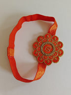 Embroidered stone embellished flower shaped stretchable headband for baby girl.Golden brocade bonnet,paithani booties,fabric headbands all these Handcrafted accessories for Newborn are perfect add ons to any traditional attire.Designer baby mats, set of generic bloomers are the other naming ceremony essentials.