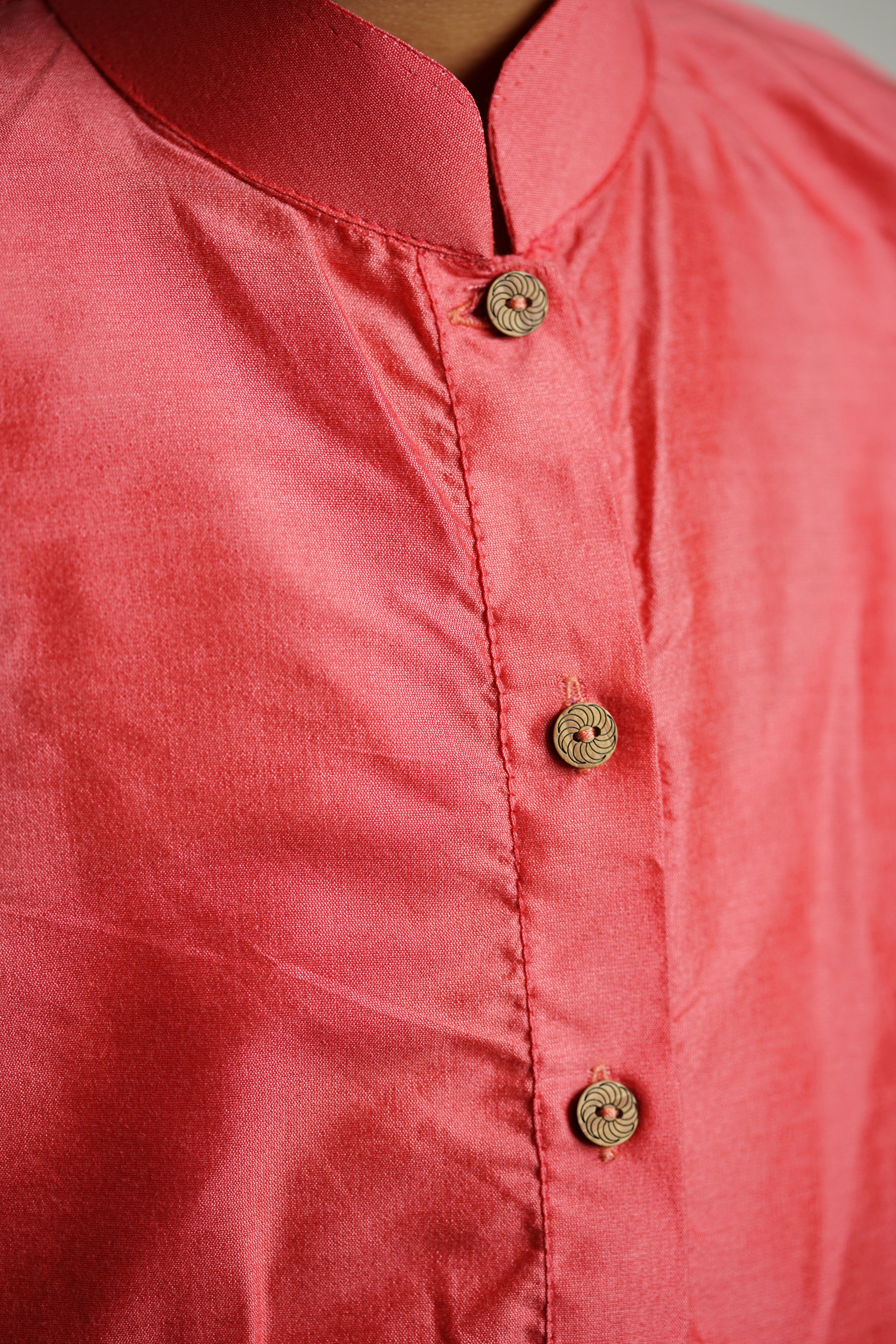 Carrot Pink cotton silk stand collar long kurta with wooden buttons.Kurtas with collar or Angrakha pattern teamed with salwar are the best choice for any festive occasion for boys.They are Trendy, Easy to wear and comfortable to carry.