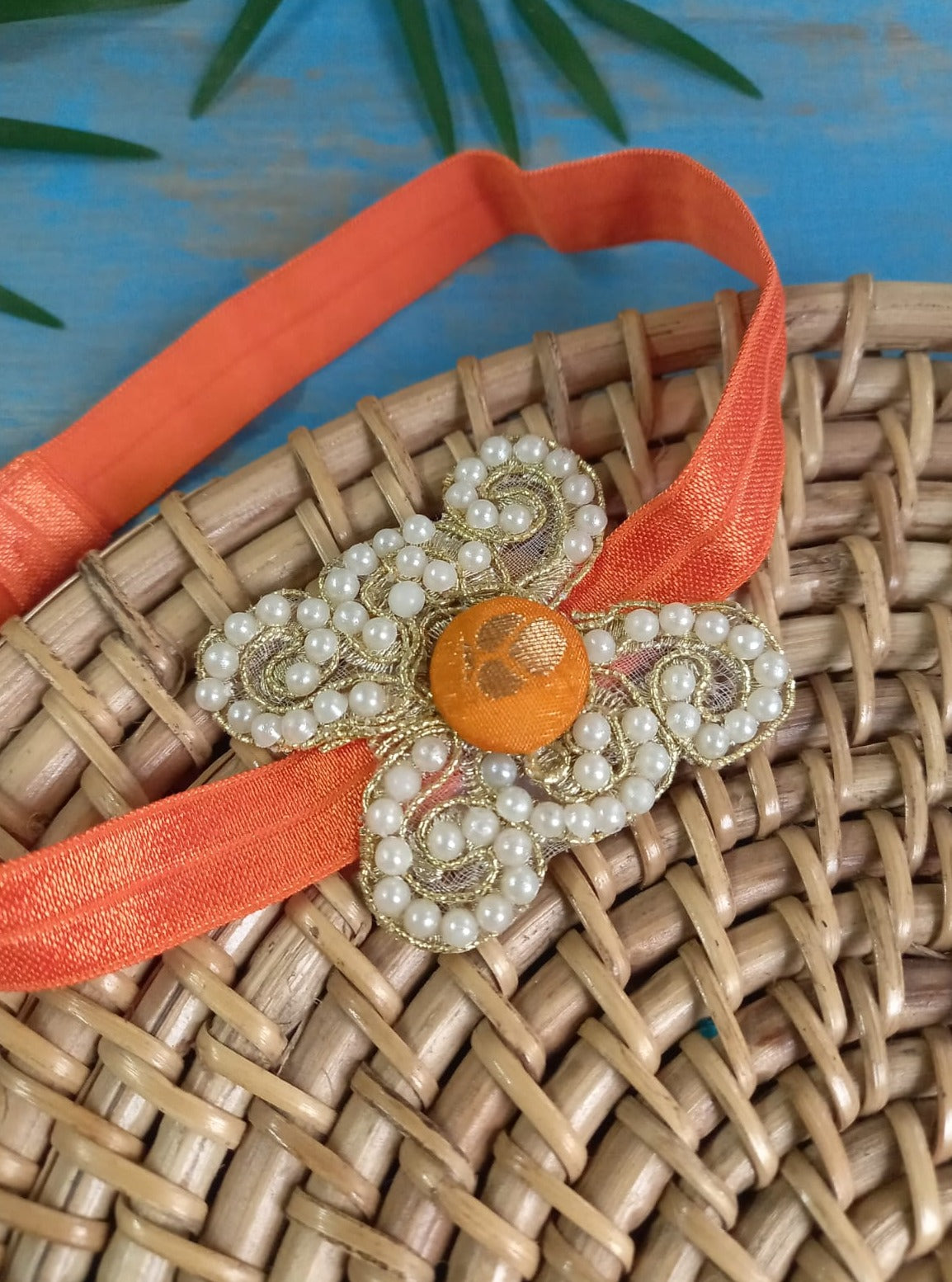 Pearl embellished stretchable Orange headband for a baby. Golden brocade bonnet, paithani booties, cute fabric headbands all these Handcrafted accessories for Newborn are perfect add ons to any traditional attire of the baby. Designer baby mats, set of generic bloomers are the other naming ceremony essentials.